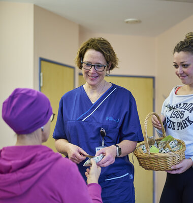 Pflegekräfte übergeben ein Geschenk an eine Patientin